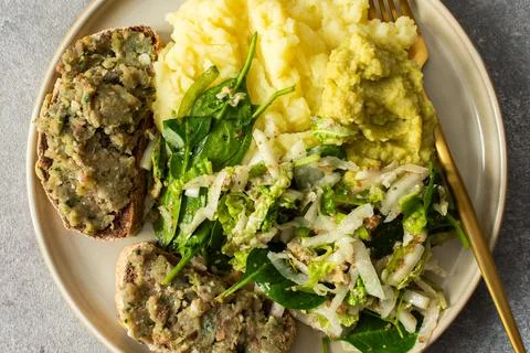 A plate shows a serving of boiled potatoes with hummus, a gluten free bread s Stock Photos
