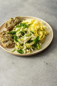 A plate shows a serving of boiled potatoes with hummus, a gluten free bread s Stock Photos