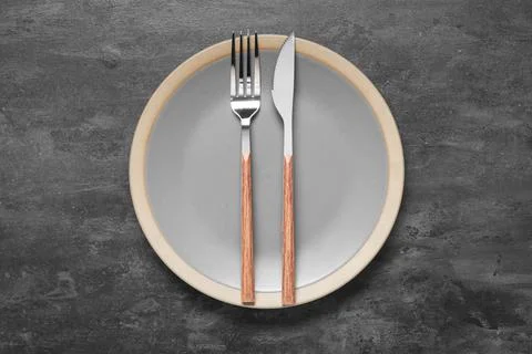 Plate with silver fork and knife on black grunge background Stock Photos