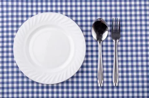 Plate with silverware on checquered blue  background. Stock Photos