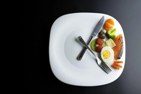 A a plate simulating a clock with the hands of a fork and a knife Stock Photos