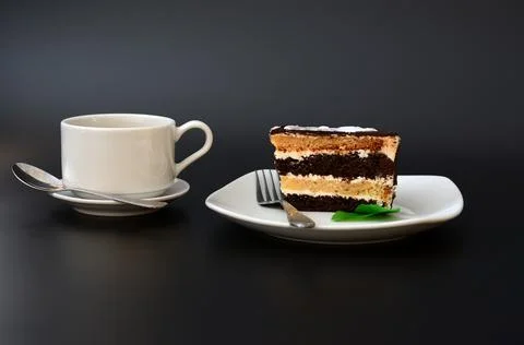 A plate with a slice of mint layered chocolate cake and a cup of hot drink .. Stock Photos