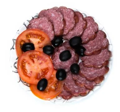 Plate of sliced sausage, tomato and olives on white background Stock Photos