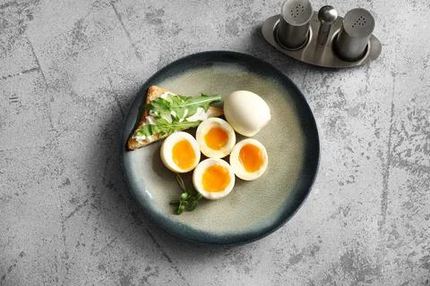 Plate with soft boiled eggs and micro green on grey background Stock Photos