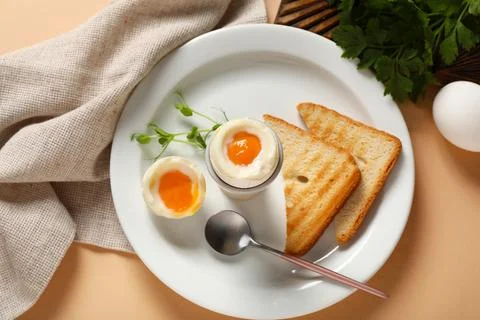 Plate with soft boiled eggs, micro green and slices of bread on beige backgro Stock Photos