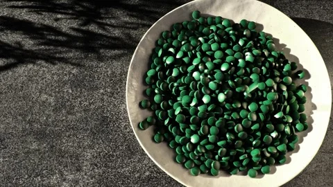 Plate of spirulina on a gray background. Algae tablets Stock Footage 317634742