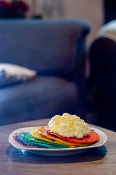 A Plate With A Stack Of Colorful Pancake With Cream On Top Stock Photos