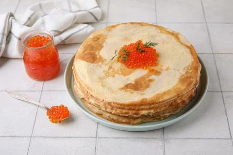 Plate with stack of delicious pancakes and red caviar on white tile backgroun Fotos de archivo