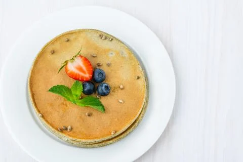 On a plate is a stack of hemp flour pancakes. Decorated with blueberries, str Stock Photos
