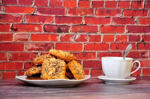 A plate with a stack of shortbread cookies with peanuts and a cup of black te Stock Photos