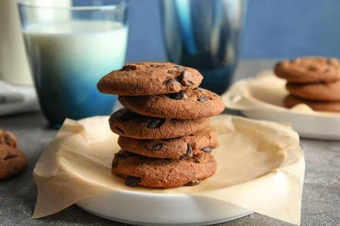 Plate with stack of tasty chocolate chip cookies on table Stock Photos