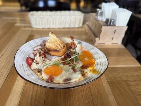 Plate of sunny side up eggs with bacon and toast on a wooden table in a coz.. Stock Photos