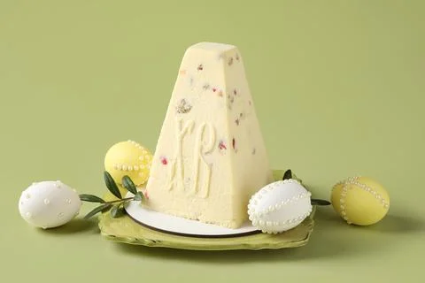 Plate with tasty curd Easter cake, eggs and leaves on green background Stock Photos