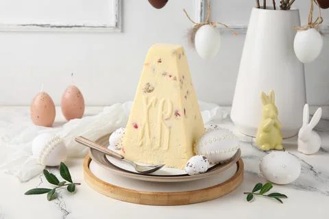 Plate with tasty curd Easter cake, eggs and decor on light background Stock Photos