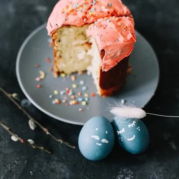 Plate with tasty Easter cake, eggs and willow branches on dark background Stock Photos