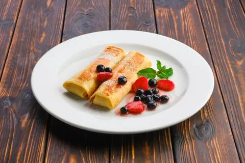 Plate with thin pancakes stuffed with curd and served with berry jam Foto stock