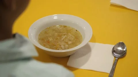 A plate of vegetable soup is placed in front of the child. Stock Footage 139754027