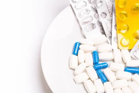 Plate with white and blue medical pills for treating diseases Stock Photos