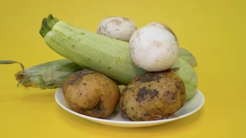 A plate with zucchini, potatoes, champignons and corn on a yellow background Stock Footage 320574255