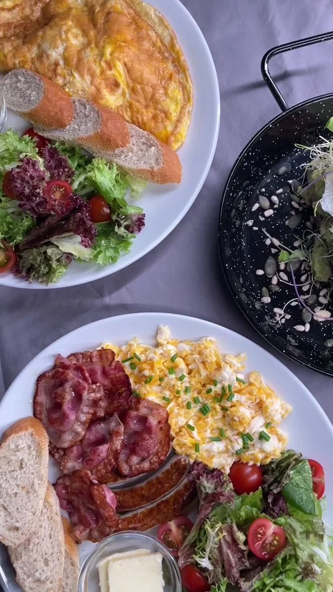 Plated brunch spread with omelette scrambled eggs bacon sausages and salads Stock Footage 341626661