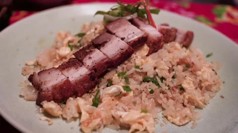 A plated crispy pork belly served over egg fried rice. 動画素材 326208217