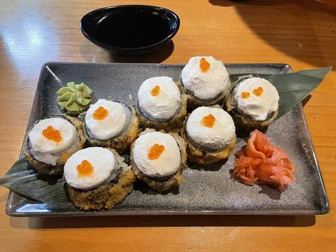 A plated dish featuring crispy tempura rolls topped with whipped cream Foto stock