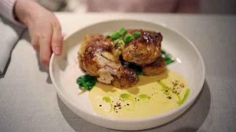 A plated roasted chicken dish served in a white restaurant bowl with golden Stock Footage 335277709