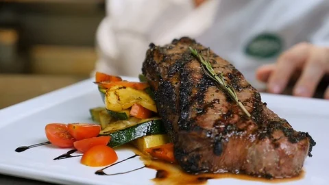Plated steak with chef in background slow motion Stockbeeldmateriaal 94271136