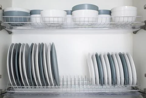 The plates are flat and deep stacked on the dryer in the kitchen Stock Photos