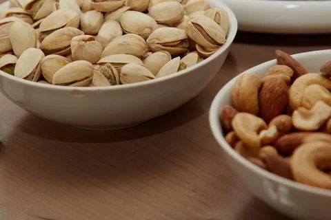 Plates with different nuts on a table, pistachios, almonds and cashews in bow Stock Photos