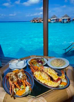 Plates with lobster on table at window with view on ocean Foto stock