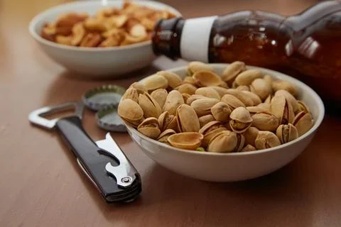 Plates with nuts on a table with a beer bottle and bottle opener, beer party, Stock Photos