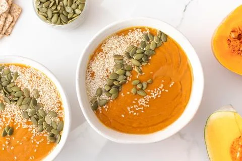 Plates with pumpkin soup puree, pumpkin and sesame seeds. Autumn menu. Stock Photos
