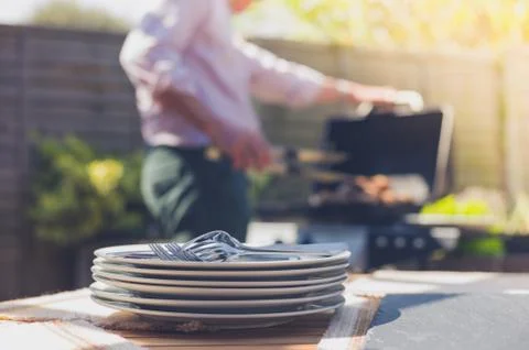 Plates on a table outside with man in background Stock Photos