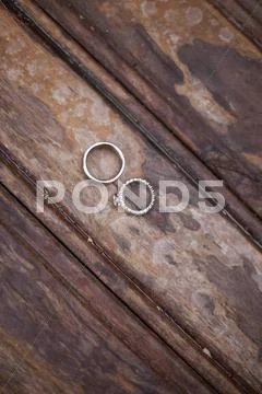 Platinum Wedding Rings . Two Rings On A Worn Scrubbed Stained Wooden Surface.