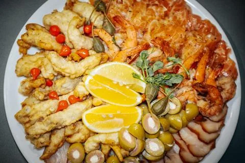 Platter of assorted seafood including fried fish, shrimp, olives, and lemon.. Stock Photos