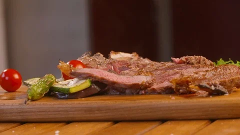 Platter of cooked and sliced meat with veggies assembled on wooden board Video stock 86171333