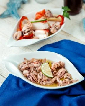 Platter of squids garnished with lemon served on white table Stock Photos