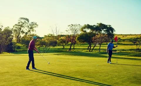 Play the course not your opponent. two friends playing a round of golf out on a Stock Photos