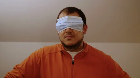 Play down the pandemic - young man wears the mask over his eyes - indoor Stock Footage 142914564