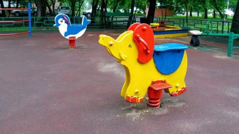 Play ground in summer park, empty swing and rocking horse Stock Photos
