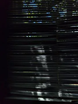 Play of light and shadow from horizontal window blinds on dark background Stock Photos
