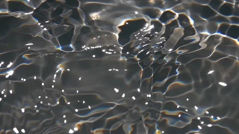 Play of sun light in waving shallow water with gray scratched bottom close up. Stock Footage 96888034
