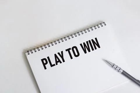 Play to Win written on a notebook with a pen on a white background Stock Photos