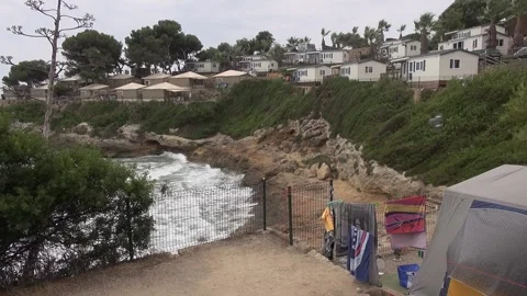 Playa de la Mora beach camping houses cloudy overcast wind trees tent Stock Footage 328831524