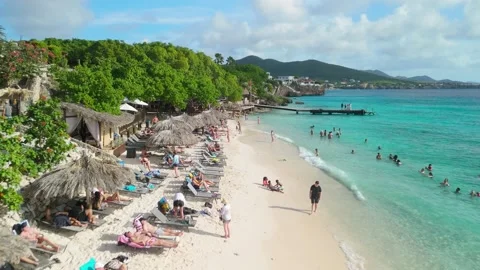 Playa Kalki crowded sandy beach in Curacao with resting tourists sunbeds and Stockbeeldmateriaal 339110466