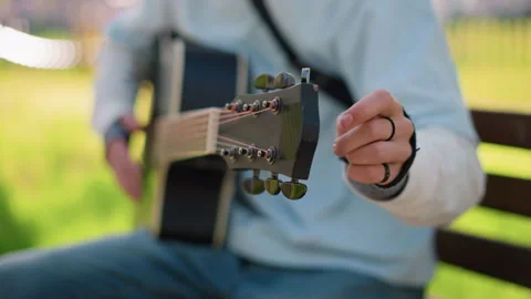 Player adjusts strings and pegs. Musician calibrates acoustic guitar for Stock Footage 327986368