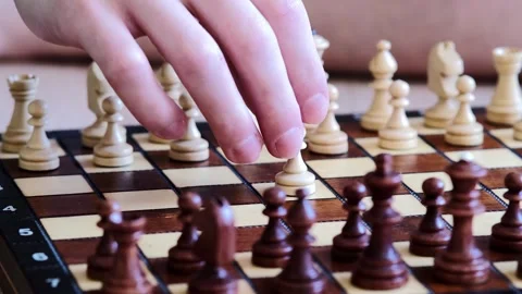 Player carefully advances pawn in chess match, Intensive concentration shown as Stock Footage 320542444
