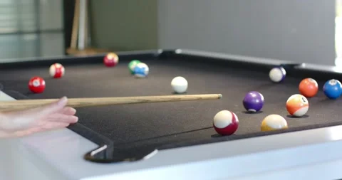 Player lining up and striking white cue ball on felt pool table, sending balls Stock Footage 339652099