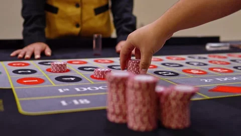 Player placing chips on roulette table with dealer Stockbeeldmateriaal 315896048